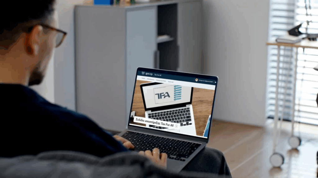 Man using laptop accessing the Cyprus Tax For All (TFA) system support page on gov.cy website.